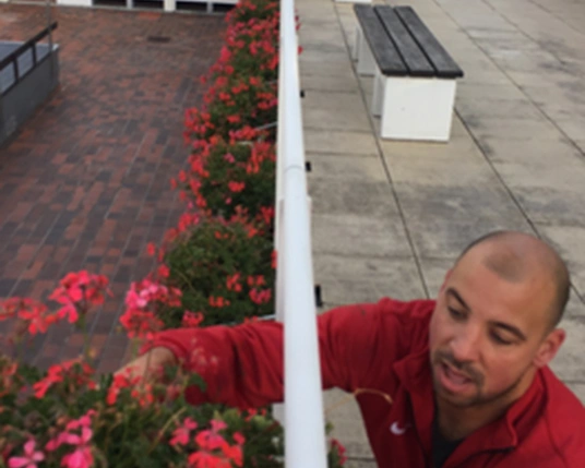 LAGO Kortrijk-Abdijkaai man verzorgt de rode geraniums bovenop de buiten kleedcabines